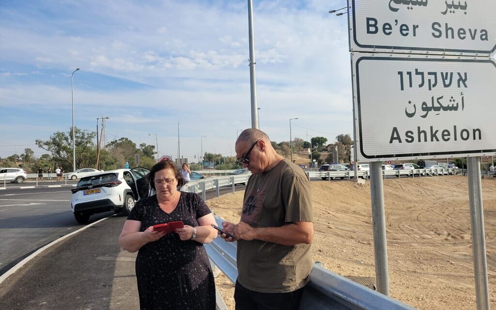 Rachel and Boaz Sadeh study their phones as they wait for a sign of life from their son, Ziv, on October 7, 2023, near Ofakim. (Canaan Lidor/Times of Israel)