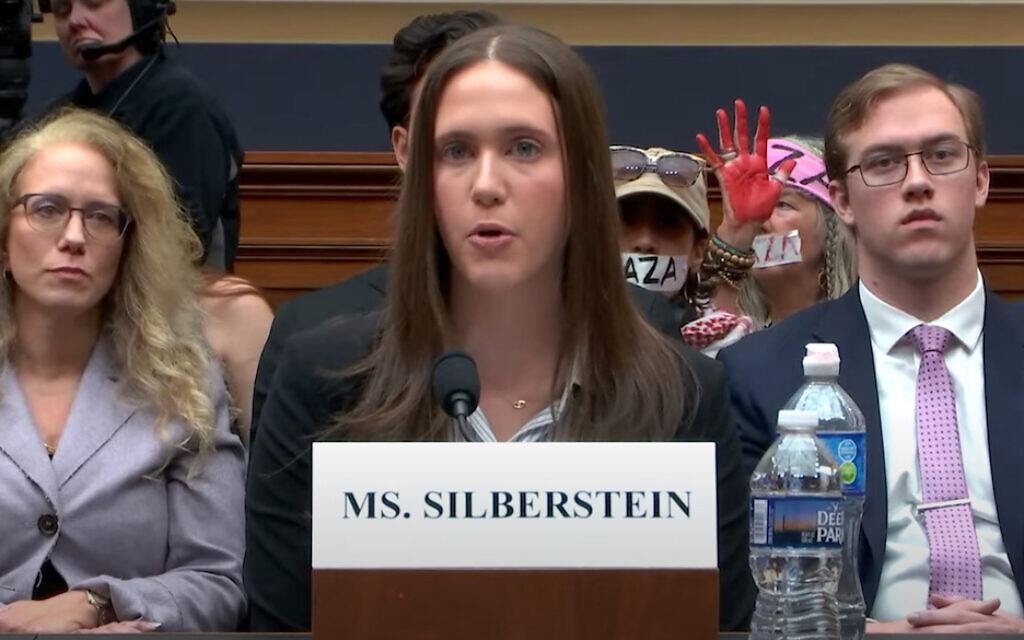 Amanda Silberstein, a Jewish Cornell University student, testifies before the US House on the antisemitism she has experienced on campus; pro-Palestinian, anti-Israel protesters demonstrate behind her, Washington, DC, November 8, 2023. (Screenshot via YouTube)