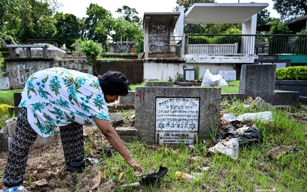 This picture taken on February 26, 2019, shows an Indonesian woman picking up rubbish around one of the Jewish tombs at a Christian cemetery in a Muslim majority neighborhood in Jakarta, Indonesia. (Photo by BAY ISMOYO / AFP)