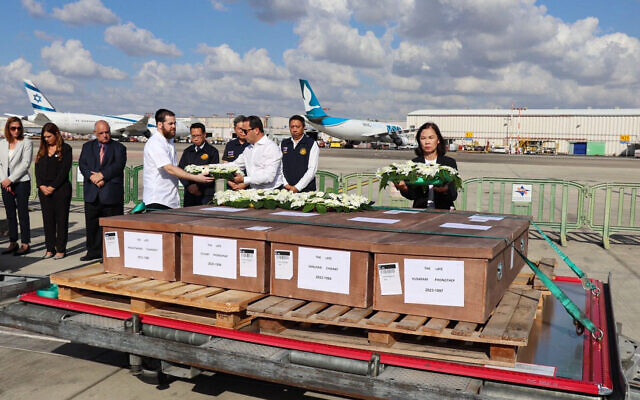This handout picture released by Thailand's Ministry of Foreign Affairs on October 20, 2023, shows coffins of Thai workers killed in the Hamas assault during a ceremony attended by Thailand's ambassador to Israel Pannabha Chandraramya (R) and officials on the tarmac of Ben-Gurion Airport in Tel Aviv on October 19, 2023, before being repatriated to Bangkok.  (Photo by Handout / THAILAND'S MINISTRY OF FOREIGN AFFAIRS / AFP)
