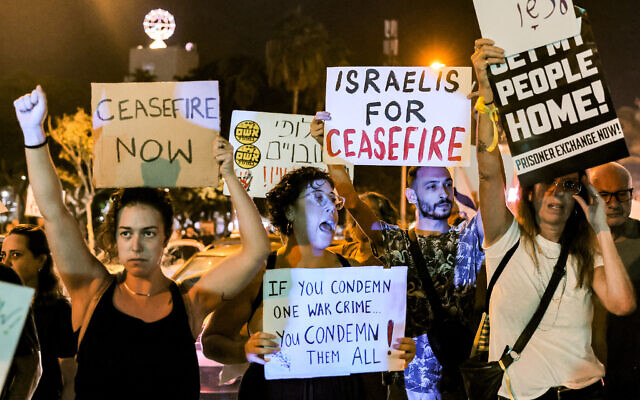 Illustrative: People gather with signs calling for a ceasefire during a protest for the release of hostages held in Gaza by Palestinian terrorists since the October 7 attack, near the Defense Ministry headquarters in Tel Aviv on October 28, 2023. (AHMAD GHARABLI / AFP)
