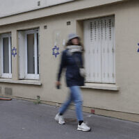 A woman walks along a building whose facade is covered with Stars of David painted during the night, in the Alesia district of Paris, on October 31, 2023. (Geoffroy Van der Hasselt/AFP)