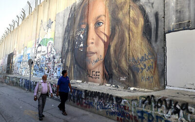 Men walk past a section of Israel's security barrier painted with a portrait of Palestinian detainee Ahed Tamimi, on November 6, 2023 in Bethlehem in the West Bank.(HAZEM BADER / AFP)