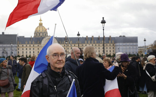 A protester stands next to flags of France during a march against antisemitism in Paris, on November 12, 2023. (Photo by Geoffroy Van der Hasselt / AFP)