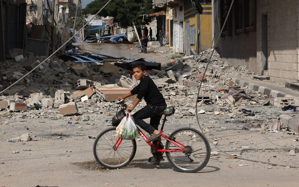 A Palestinian boy rides a bicycle amidst debris in Rafah, in the southern Gaza Strip on November 13, 2023, amid the ongoing battles between Israel and the Palestinian terror group Hamas. (Photo by MOHAMMED ABED / AFP)