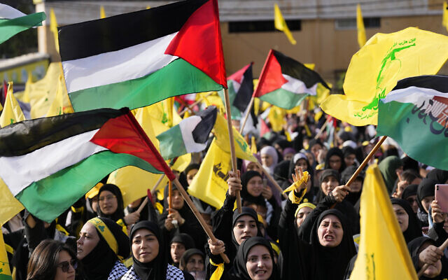 Supporters of Iranian-backed Hezbollah raise their fists and cheer as leader Hassan Nasrallah appears via a video link during a rally in Beirut, Lebanon, November 3, 2023. (AP Photo/Hussein Malla)