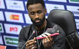 Israel team captain Eli Dasa shows a shoe of a kidnapped Israeli boy during a press conference, before a training session for the Euro 2024 group I qualifying soccer match between Israel and Switzerland at the Pancho Arena in Felcsút, Hungary, November 14, 2023. The shoe belongs to 8-year-old Nave Shoham, who along with seven relatives was taken captive in the Hamas terror group's October 7 onslaught.(AP Photo/Denes Erdos)