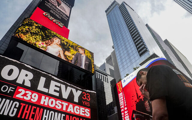 Michael Levy lowers his head as he becomes emotional after the unveiling of a Times Square digital billboard showing posters of Hamas hostages taken by terrorists, including his older brother Or Levy, during an Oct. 7 assault into Israel, Friday, Nov. 17, 2023, in New York. (AP Photo/Bebeto Matthews)