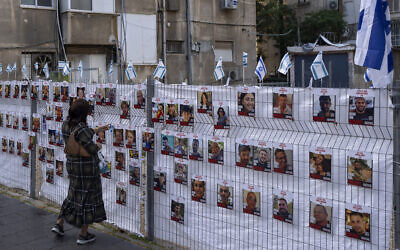 A woman looks at photographs of hostages held in Gaza displayed in Ramat Gan on November 22, 2023. (AP Photo/Oded Balilty)