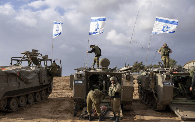 IDF soldiers work on armored military vehicles along Israel's border with the Gaza Strip, November 20, 2023. (AP Photo/Ohad Zwigenberg)