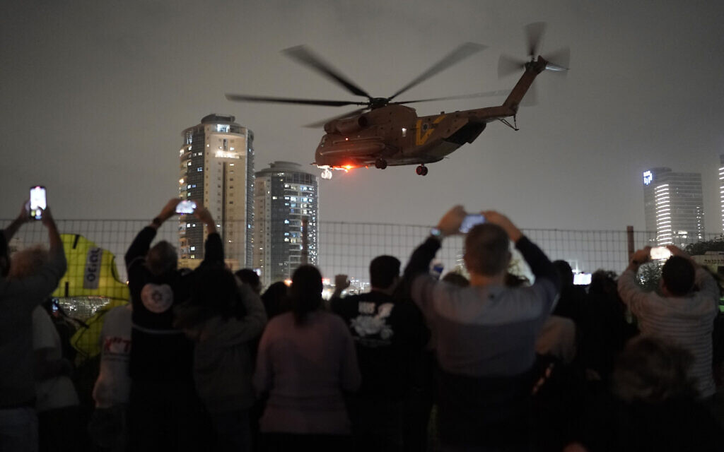 A group of Israelis watch as a helicopter carrying hostages released from the Gaza Strip lands at the helipad of the Schneider Children's Medical Center in Petah Tikva, Israel, Sunday Nov. 26, 2023.(AP/Leo Correa)