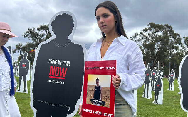 Mika Shani, sister of Hamas hostage Amit Shani, holds a photo of her brother in front of cardboard cutouts representing Israeli hostages, during a protest outside Parliament House in Canberra, Australia, November 28, 2023. (AP Photo/Rod McGuirk)