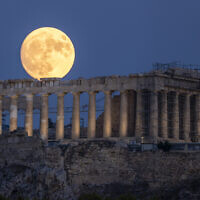 The moon rises in the sky behind the 5th century BCE Parthenon temple at the ancient Acropolis hill, in Athens, July 31, 2023. (Petros Giannakouris/AP)