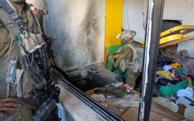Troops guard the entrance to a tunnel found inside a home in northern Gaza. The entrance was hidden underneath a bed in a children's room, November 7, 2023. (Emanuel Fabian/Times of Israel)