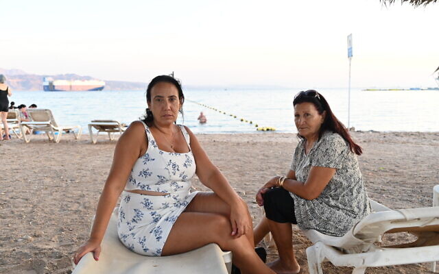 Netivot evacuees Limor Abergil, left, and her mother Shula sit on a beach in Eilat, on October 30, 2023. (Canaan Lidor/Times of Israel)