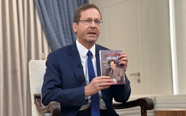 President Isaac Herzog holds up an Arabic version of 'Mein Kampf' found on the body of a Hamas fighter in the Gaza Strip, during an interview with the BBC, November 12, 2023. (President's Residence)
