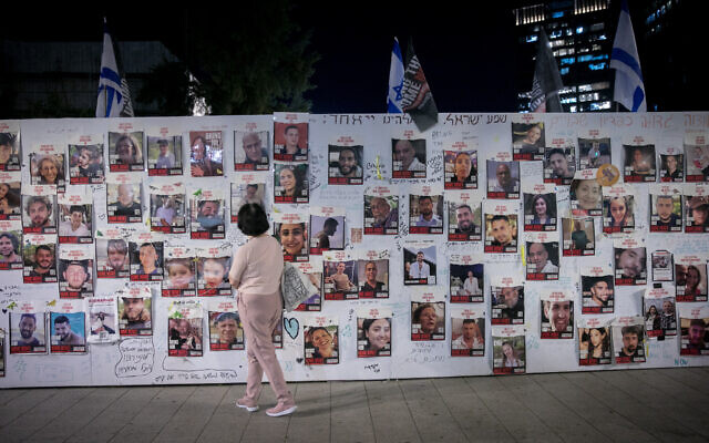 A woman stands in front of photographs of Israelis held hostage by Hamas terrorists in Gaza, outside Defense Ministry headquarters in Tel Aviv, on November 9, 2023 (Miriam Alster/FLASH90)