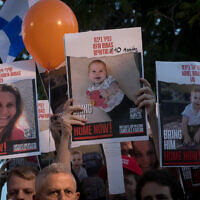 Israelis hold photographs of the Bibas family at a press conference calling for the release of 10 month old Kfir, 4 year old Ariel, and their parents Shiri and Yarden. at "Hostages Square" in Tel Aviv, November 28, 2023. (Miriam Alster/Flash90)