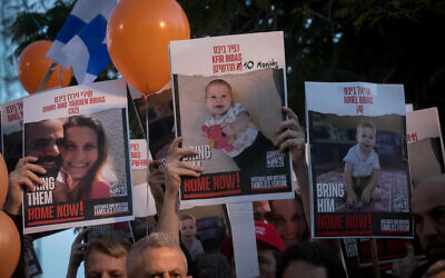 Israelis hold photographs of the Bibas family at a press conference calling for the release of 10 month old Kfir, 4 year old Ariel, and their parents Shiri and Yarden. at "Hostages Square" in Tel Aviv, November 28, 2023. (Miriam Alster/Flash90)