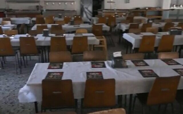 A table set at the dining hall of Kibbutz Nir Oz with posters of those murdered and kidnapped in Hamas's October 7 massacre, November 14, 2023. (Channel 12 screenshot: used in accordance with Clause 27a of the Copyright Law)