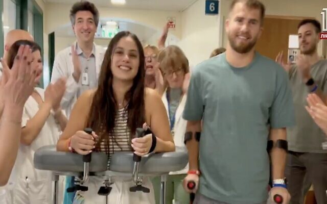 Gali Segal and Ben Binyamin walk in a hospital where they're rehabbing after each losing their right leg during the October 7 onslaught, in a clip aired by Channel 12 on November 17, 2023. (Screen capture/Channel 12)