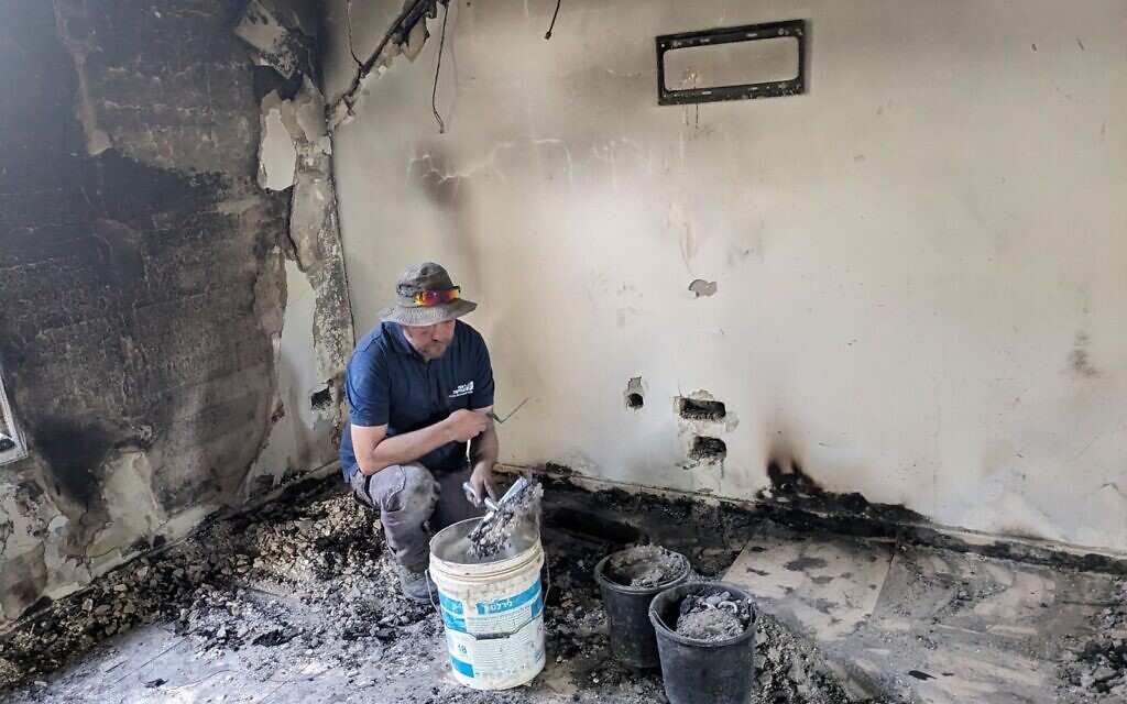 Archaeologist Oren Shmueli collects material from a burned home in Kibbutz Nir Oz to be sifted on November 9, 2023. (Melanie Lidman/Times of Israel)