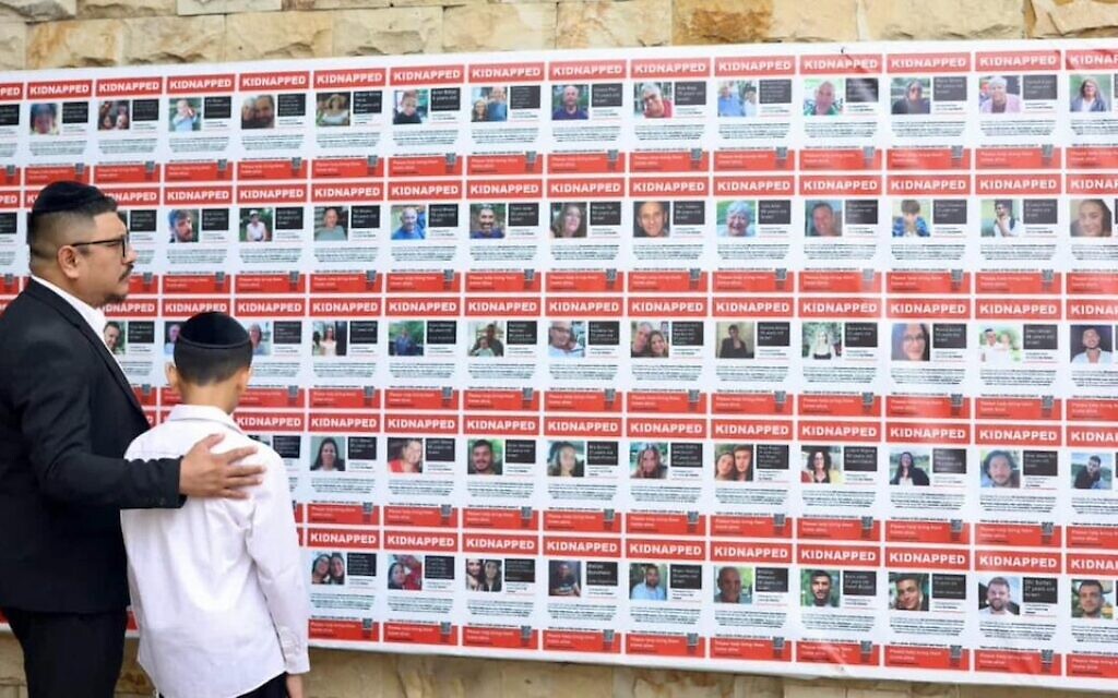 Rabbi Yaakov Baruch looks at posters with the names and images of Israelis taken hostage by Hamas. (Courtesy of Baruch via JTA)