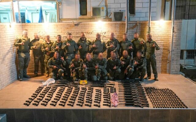 Police officers pose with weapons seized on the Jordan border, November 23, 2023. (Israel Police)