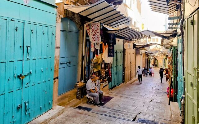 A souvenir shop owner sits on a nearly empty street in Jerusalem's Old City, following a halt in the tourist influx due to the Israel-Hamas war, November 6, 2023 (Gianluca Pacchiani/Times of Israel)
