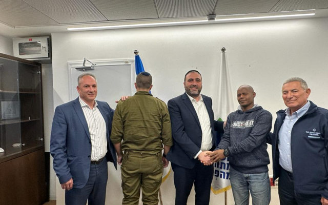 Interior Minister Moshe Arbel (center) shaking the hand of Eritrean Mulugeta Tsagi, who saved the life of an IDF officer (second from left), November 26, 2023. (Interior Ministry)