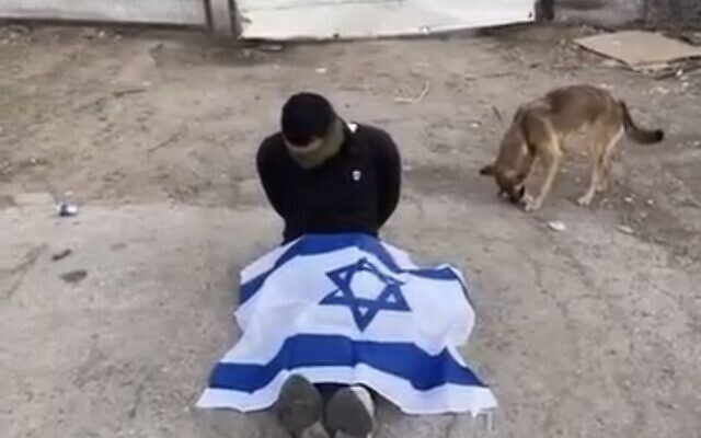 A detained Palestinian forced to sit blindfolded with an Israeli flag on his legs, West Bank, October 31 or a few days prior, 2023 (X, screenshot)