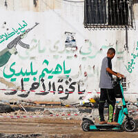 A Palestinian youth rides his scooter in the Tulkarem refugee camp in the West Bank on November 7, 2023, following an overnight raid by Israeli troops amid ongoing battles between Israel and the Hamas terror group. (Photo by Zain JAAFAR / AFP)