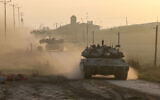 Israeli military vehicles drive near the border with the Gaza Strip on December 3, 2023. (Menahem KAHANA / AFP)