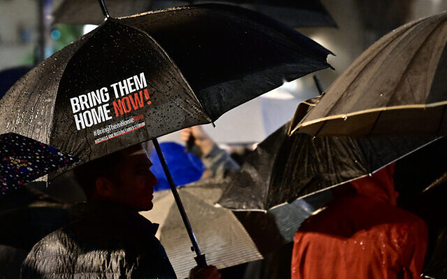 A protester carries an umbrella calling for the return of Israeli hostages held in Gaza since the October 7 attack, in Tel Aviv on December 23, 2023. (Alberto PIZZOLI / AFP)