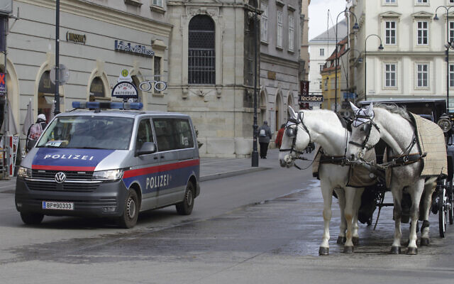 File: A police van drives past Fiaker horses at St. Stephen's Cathedral in Vienna, Austria, March 15, 2023. (AP Photo/Heinz-Peter Bader)