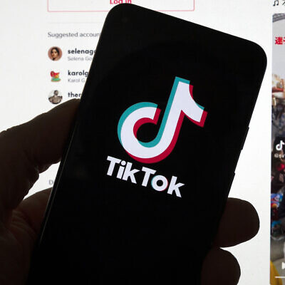 Illustrative: The TikTok logo is seen on a mobile phone in front of a computer screen which displays the TikTok home screen, March 18, 2023. (AP/Michael Dwyer)
