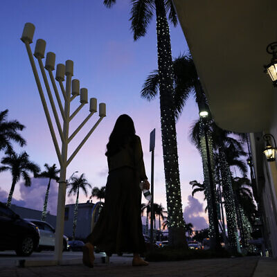 A woman walks past a menorah standing outside a Jewish synagogue ahead of the start of Hanukkah, in Miami Beach, Florida, December 1, 2023. (Rebecca Blackwell/AP)