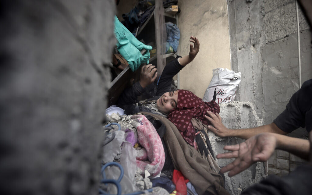 Palestinians try to rescue a woman stuck under the rubble of a destroyed building following Israeli airstrikes in Khan Younis refugee camp, southern Gaza Strip, Thursday, Dec. 7, 2023. (AP Photo/Mohammed Dahman)