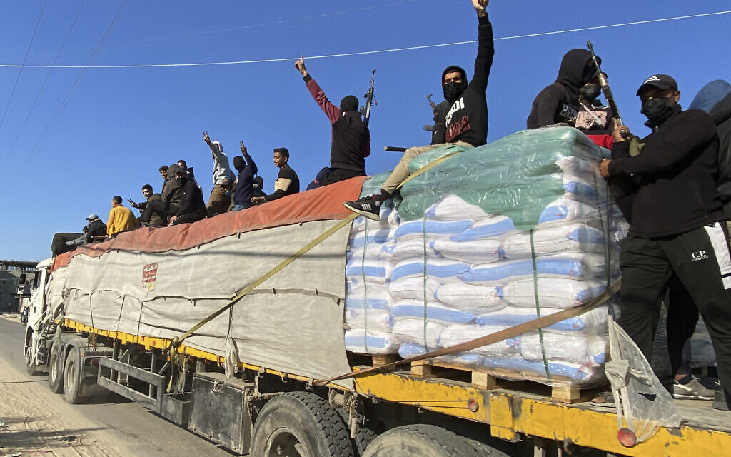 Armed members of the Hamas terror group ride atop a humanitarian aid truck in Rafah, Gaza Strip, December 19, 2023. (AP)