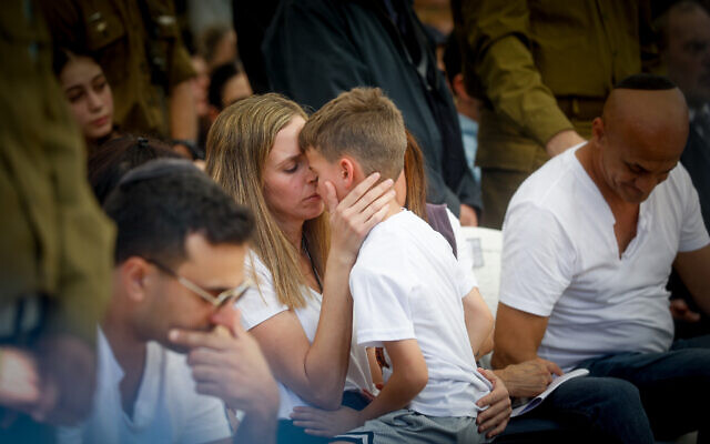 Col. Asaf Hamami's wife Sapir and son Alon mourn during his funeral in Kiryat Shaul Cemetery in Tel Aviv, December 4, 2023, (Miriam Alster/Flash90)