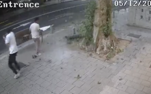 Surveillance camera footage from Tel Aviv captures the moment a large piece of shrapnel from an interception missile falls out of the sky, narrowly missing two pedestrians, December 5, 2023. (Screenshot, used in accordance with Clause 27a of the Copyright Law)