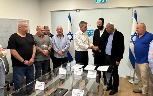 Moshe Edri, the head of the Tekuma Authority, wearing a white shirt, attends a signing ceremony at the authority's offices in the Sorek Region on December 24, 2023. (Courtesy of Tekuma Authority)