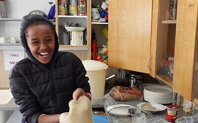 Nine-year-old Bena Hagdu holds injera bread at the Hannaton Educational Center at Kibbutz Hanaton, December 2023. (Omer Sharvit/ Zman)