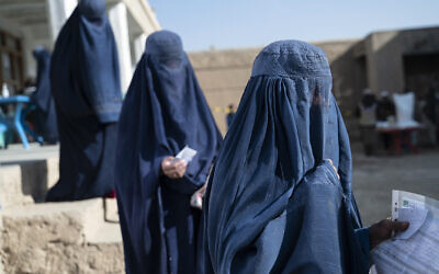 Afghan burqa-clad women stand in a queue as they wait to receive food being distributed as an aid by the World Food Programme (WFP) organization at Nawabad Kako Sahib area in Baraki Barak district of Logar Province on January 7, 2024. (Wakil Kohsar/AFP)