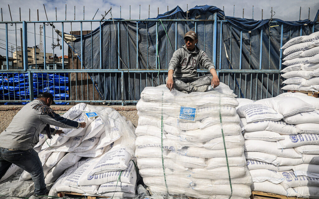 A worker rests as displaced Palestinians receive food aid at the United Nations Relief and Works Agency for Palestine Refugees (UNRWA) center in Rafah in the southern Gaza Strip on January 28, 2024. (Photo by AFP)