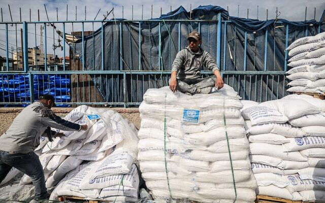 A worker rests as displaced Palestinians receive food aid at the United Nations Relief and Works Agency for Palestine Refugees (UNRWA) center in Rafah in the southern Gaza Strip on January 28, 2024. (AFP)