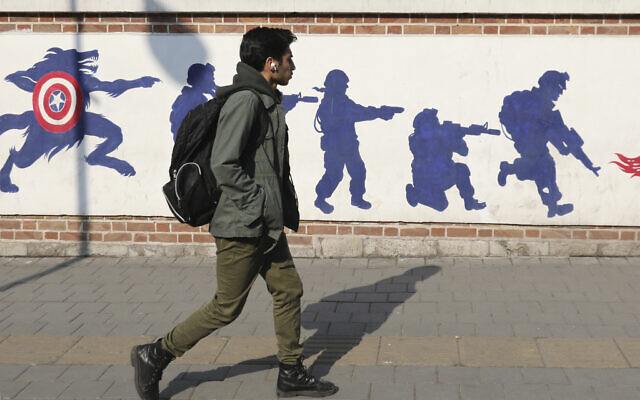 A young man walks past anti-US graffiti outside the building formerly hosting the embassy of the United States in Tehran on January 30, 2024. (Atta Kenare/AFP)