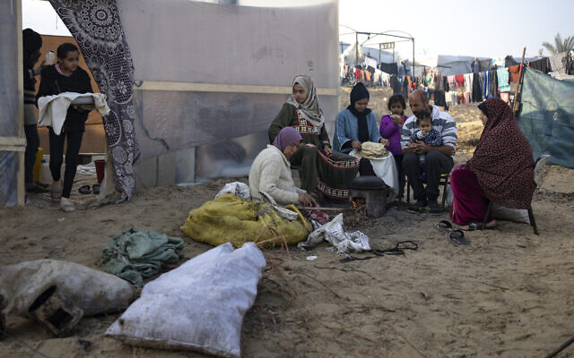 Members of the Abu Jarad family, who were displaced by the war between Israel and Hamas in the Gaza Strip, bake bread at a makeshift tent camp in the Muwasi area, southern Gaza, January 1, 2024. (AP Photo/Fatima Shbair)