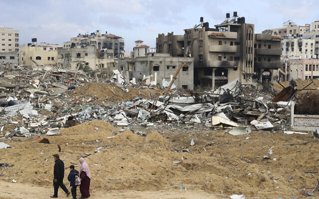 Palestinians walk past destroyed buildings in Gaza City on Wednesday, Jan. 3, 2024. (AP/Mohammed Hajjar)
