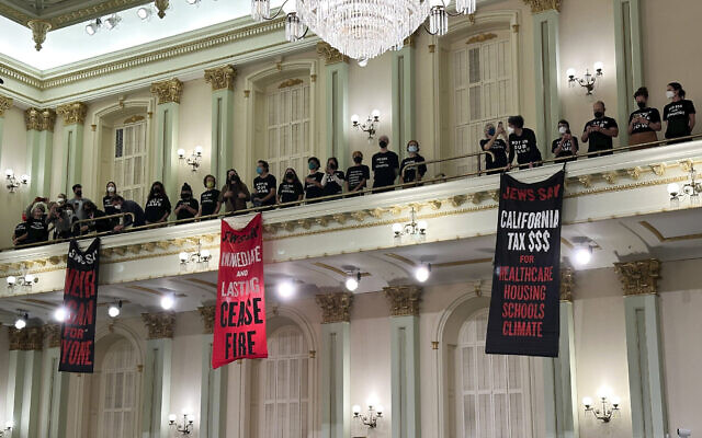 Protesters calling for a ceasefire in the Israel-Hamas war stand and sing in the Assembly chamber of the State Capitol in Sacramento, Calif., Wednesday, Jan. 3, 2024. The Assembly adjourned shortly after the protest began. (AP/Adam Beam)